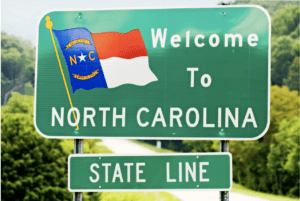 Map of North Carolina says welcome to North Carolina and then "State Line" underneath it on a separate green sign.