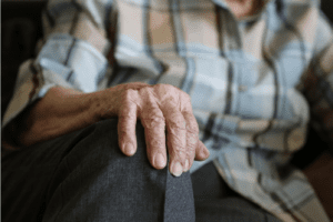 image shows the hands of an elderly woman putting her hand on her knee