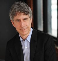 Image of white man half-smiling wearing a suit jacket. He is author and law professor Joel Bakan.